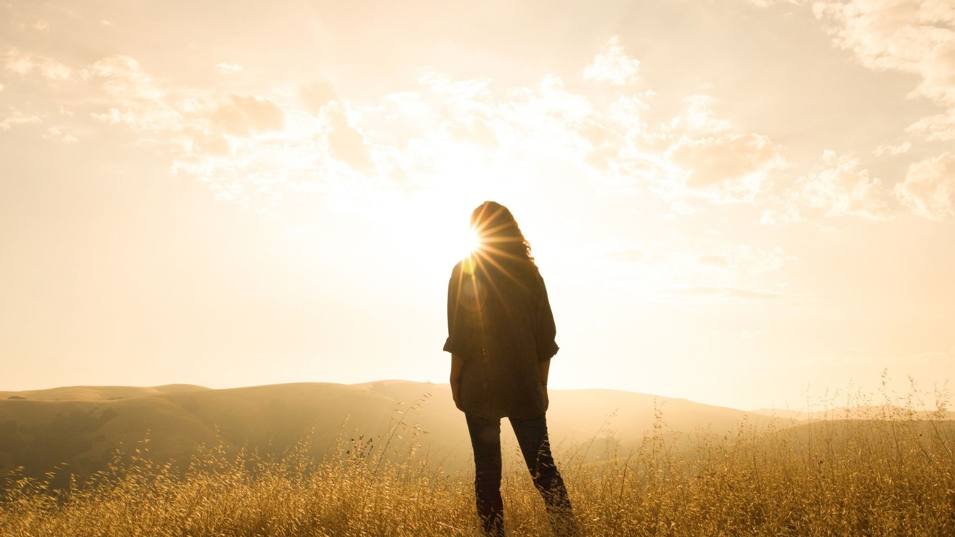 Woman standing in field in front of the sun